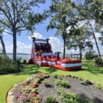 Tropical red inflatable water slide on a lakeside lawn in Conroe, TX